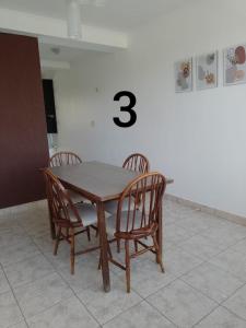 una mesa de madera con cuatro sillas y un número tres en Duplex Houssay. en Aldea Camarero