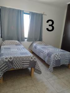 duas camas num quarto com um número três na parede em Duplex Houssay. em Aldea Camarero