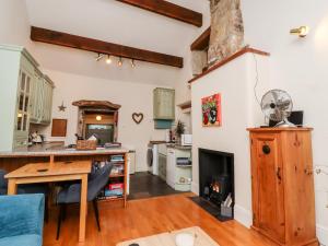 a kitchen and living room with a table and a fireplace at Yate Cottage in Oxenhope