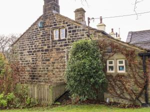 an old stone house in the middle of a yard at Yate Cottage in Oxenhope