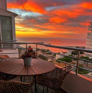 a table and chairs on a balcony with a sunset at Sunsetmare Vacational Apartment in Roses
