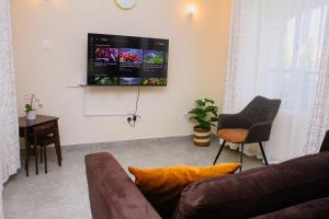 a living room with a couch and a tv on the wall at Twin Palms Apartments, Bamburi, Mombasa in Mombasa