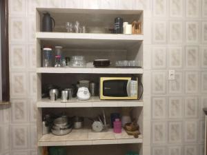 a shelf with a microwave and other kitchen items at Casa de Praia em Itaparica in Itaparica