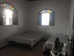 a small room with two beds and two windows at Casa de Praia em Itaparica in Itaparica