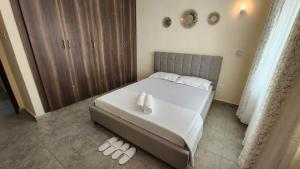 a bedroom with a bed with two slippers on the floor at Twin Palms Apartments, Bamburi, Mombasa in Mombasa