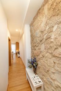 Habitación con una pared de piedra con un banco y flores en Apartamentos Coruña Vip Centro, en A Coruña