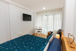 1 dormitorio con 1 cama azul y TV en Apartamentos Coruña Vip Centro, en A Coruña
