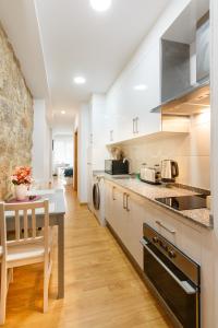 cocina con armarios blancos y encimera en Apartamentos Coruña Vip Centro, en A Coruña