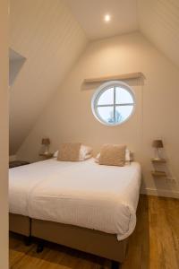 a bedroom with a large bed with a window at Villa Zuiderduin cottage in Zoutelande