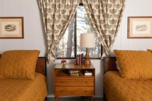 1 Schlafzimmer mit 2 Betten und einem Tisch mit einem Fenster in der Unterkunft 2407 - Oak Knoll #9 cabin in Big Bear Lake