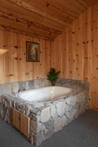 Una gran bañera de piedra en una habitación con paredes de madera. en 2412 - Oak Knoll Studio with Jacuzzi #15 cabin en Big Bear Lake