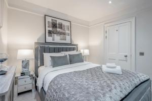 a white bedroom with a large bed and a table at Tottenham Court's House - 2 Bed in London