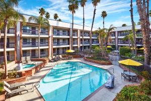 an apartment building with a swimming pool and palm trees at Best Western Plus Meridian Inn & Suites, Anaheim-Orange in Orange