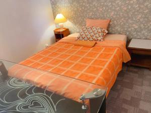 ein Schlafzimmer mit einem Bett mit einer orangefarbenen Bettdecke und einem Schreibtisch in der Unterkunft 住在巴黎 in Bondy