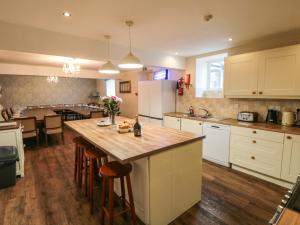 a kitchen with white cabinets and a large wooden table at Honeysuckle in Filey