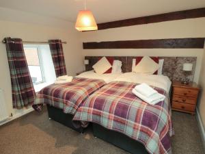 a bedroom with a large bed with a plaid blanket at Honeysuckle in Filey +31 photos