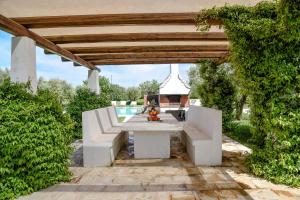 een terras met een witte bank onder een pergola bij Trulli Terrarossa con Piscina in Martina Franca