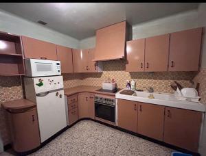eine Küche mit Holzschränken und einem weißen Kühlschrank in der Unterkunft 住在巴黎 in Bondy