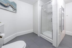 a white bathroom with a shower and a toilet at Tottenham Court's House - 2 Bed in London