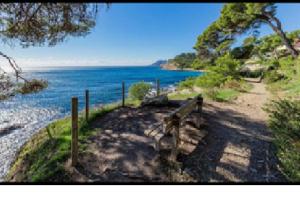 einen Weg neben dem Wasser mit einer Bank in der Unterkunft Joli T1 de la mer climatisé rénové in Saint-Mandrier-sur-Mer