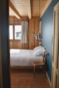 1 dormitorio con 1 cama, 1 silla y 1 ventana en Charmant demi-chalet à la montagne, en Notre-Dame-de-Bellecombe