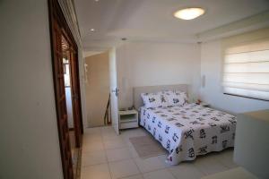 a bedroom with a white bed and a window at Apartamento duplex em Praia do Forte - 2 suítes in Praia do Forte