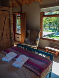 1 dormitorio con 1 cama, 1 silla y 1 ventana en La Huala en San Carlos de Bariloche
