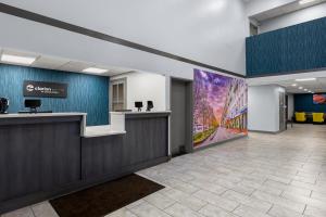 an office lobby with a reception desk and a large painting at Clarion Pointe Hinesville near Fort Stewart in Hinesville