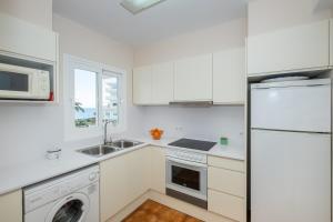 a white kitchen with a sink and a refrigerator at apartamento edificio migjorn santo tomas in Santo Tomás
