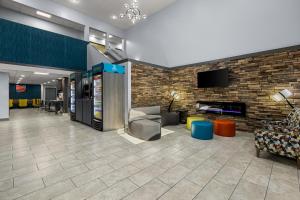 a lobby with a couch and chairs and a tv at Clarion Pointe Hinesville near Fort Stewart in Hinesville