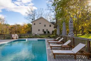 a swimming pool with chairs and a fence at Cortland by AvantStay Charming Heritage Estate w Private Lake Pool in Saugerties