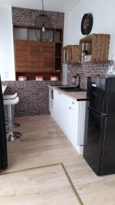 una cucina con frigorifero nero e armadietti bianchi di Gîte location meublée Aumale - studio en centre-ville - La maison en brique a Aumale
