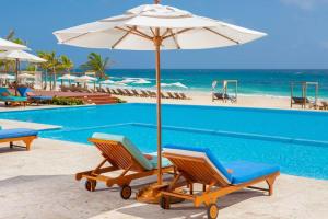 een paar stoelen en een parasol naast een zwembad bij Apartment with private jacuzzi and King bed Near Hard Rock hotel & casino in Punta Cana
