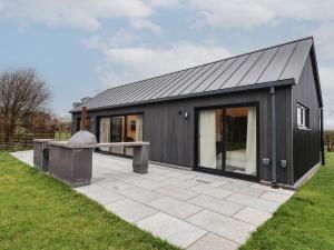 a black house with a patio in a yard at Wren in Huggate