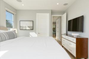 a white bedroom with a large bed and a flat screen tv at Sea Crown by AvantStay 5mins from the Beach w Multiple Terraces PermitSLP13639 in Newport Beach