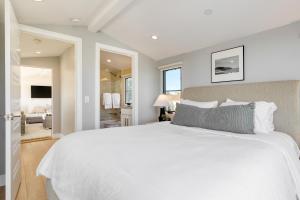 a bedroom with a large white bed and a living room at Sea Crown by AvantStay 5mins from the Beach w Multiple Terraces PermitSLP13639 in Newport Beach