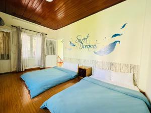 2 bedden in een slaapkamer met blauwe lakens bij Home Thỏ Vân Anh in Da Lat