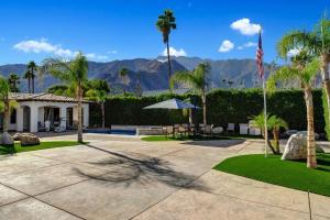 un patio con bandiera e palme e una casa di Villa Toscana by AvantStay Palatial Villa With Spa Pool Theater Game Room Permit4769 a Palm Springs