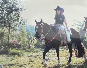 a woman riding on a horse in a field at Casa de campo com piscina in Palhoça