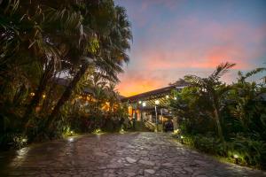 a cobblestone road in front of a building with palm trees at Hideaway Rio Celeste Hotel in Bijagua