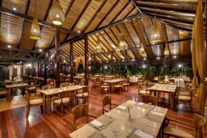 ビハグアにあるHideaway Rio Celeste Hotelのテーブルと椅子が備わるウッドフロアのレストランを併設しています。