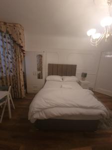Un dormitorio con una gran cama blanca y una mesa en 51 Nonsuch Walk, Cheam, en Cheam