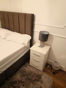 a bedroom with a bed and a nightstand with a lamp at 51 Nonsuch Walk, Cheam in Cheam