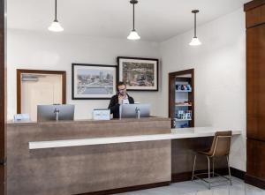 a woman talking on a phone at a reception desk at Staybridge Suites Rochester University, an IHG Hotel in Rochester