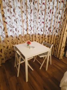 una mesa blanca con 2 sillas y un jarrón de flores en 51 Nonsuch Walk, Cheam, en Cheam