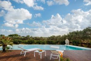 a swimming pool with chairs and a table on a deck at Villa Selinus in Castelvetrano Selinunte