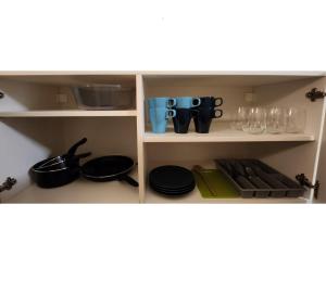 a kitchen shelf with utensils and glasses on it at Small apartment for groups in city centre in Prague