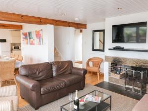 a living room with a leather couch and a fireplace at Firm Anchor in Salcombe