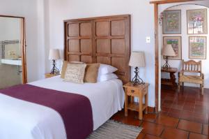 a bedroom with a large bed with a wooden headboard at Hotel los Arcos in Taxco de Alarcón