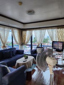 sala de estar con sofás azules y ventilador en 2BD, 2BR condo Penthouse, en Davao City